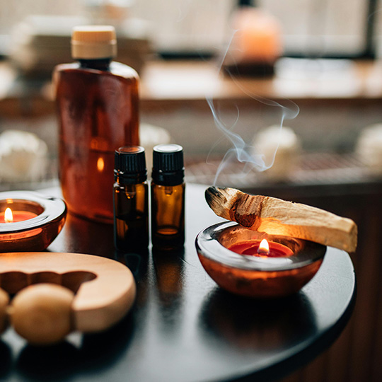 Aromaöle und brennende Kerzen auf einem Tisch – stimmungsvolles Bild zur Aromaölmassage